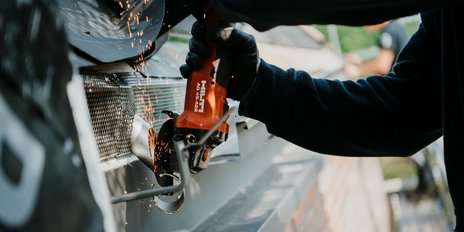 Die Nahaufnahme zeigt eine Person, die mit einer Hilti-Trennmaschine arbeitet, während Funken in der Luft fliegen.