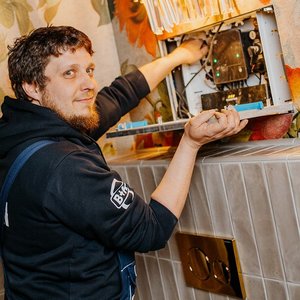 Der Techniker überprüft eine elektrische Einheit in einem stilvollen Badezimmer mit floralen Wandmotiven und modernen Fliesen.